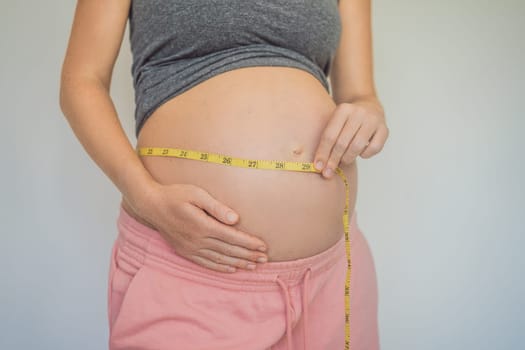 Young woman measuring her pregnant belly with inch tape. Inches, American standard. Preparation for childbirth, Girl big belly advanced healthy pregnancy.