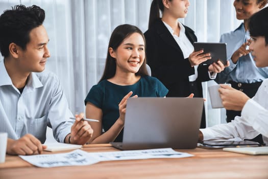 Multiracial analyst team use BI dashboard data to analyze financial report on meeting table. Group of diverse business people utilize data analysis by FIntech for success business marketing. Concord