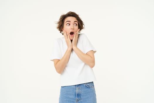 Image of woman with shocked face, looks frightened in panic, stands against white studio background. Copy space