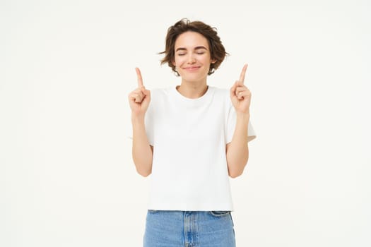 Image of carefree girl, laughing and smiling, pointing fingers up, showing promo offer, banner on top, posing over white studio background. Copy space