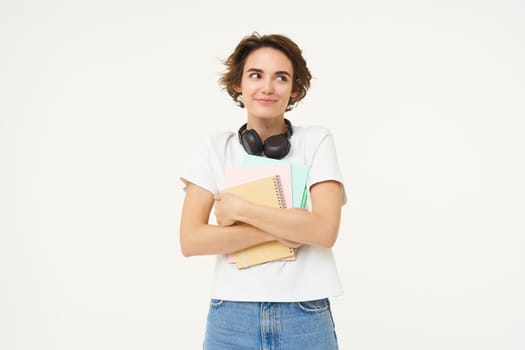 Image of stylish, modern girl student, holding workbook, documents. Woman teacher with papers standing over white background.