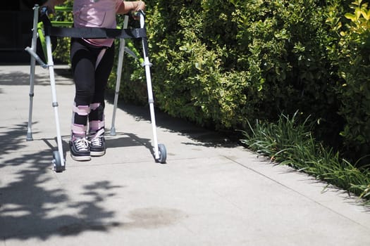 child with walking frame and knee orthosis outdoor .