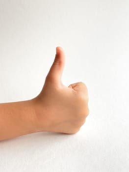 Childs hand giving a thumbs up with neutral background for positivity concept.