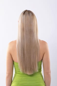 A stylish woman showcases her long hair from the back in a vibrant green dress that highlights her personality