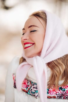 Beautiful Russian woman in a headscarf, portrait. A lovely woman smiles and looks at the camera in winter