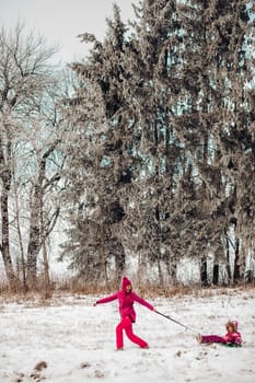 Cute family have fun in a winter park.Mom and daughter play in winter in warm clothes, have fun, hug, rejoice. Family Day