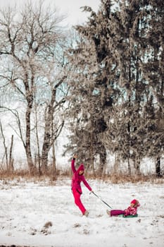 Cute family have fun in a winter park.Mom and daughter play in winter in warm clothes, have fun, hug, rejoice. Family Day