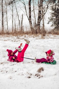 Cute family have fun in a winter park.Mom and daughter play in winter in warm clothes, have fun, hug, rejoice. Family Day