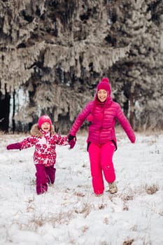 Cute family have fun in a winter park.Mom and daughter play in winter in warm clothes, have fun, hug, rejoice. Family Day