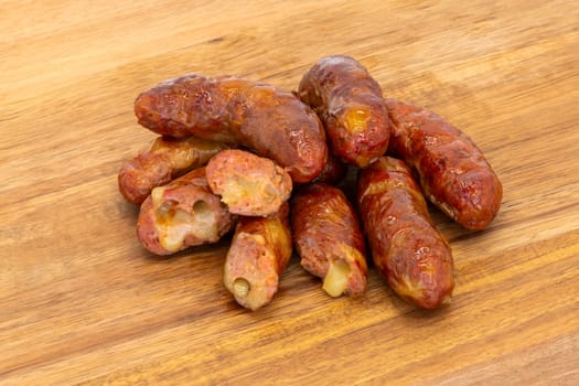 An assortment of flavorful sausages piled on a rustic wooden board, perfect for enticing appetizing visuals