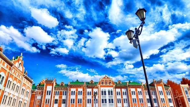 The Bruges Embankment in Yoshkar-Ola features colorful buildings lining River, set against a backdrop of dynamic clouds