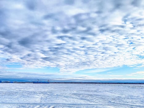 A river is melting as winter snow blankets the road, signaling the shift to spring in Arkhangelsk.