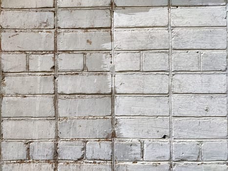 The textured surface of a brick wall displays contrasting areas of white paint wear, highlighting its age and character.