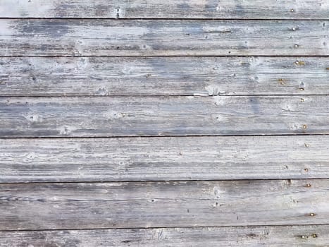 Horizontal wooden planks display a weathered gray finish, showcasing their rustic texture and character.