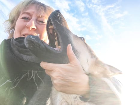 Adult girl or middle aged woman with shepherd dog and sky on the background