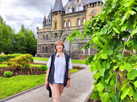 A woman enjoys her travel adventure at Garibaldi Castle, showcasing her excitement in a historic setting. The adventures of a middle-aged female tourist on a trip