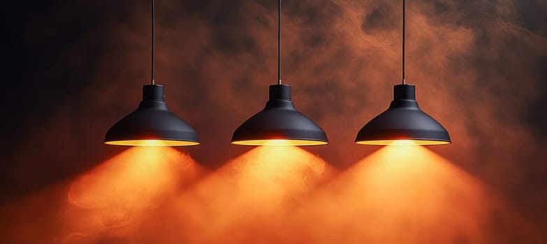 Three black ceiling lamps are hanging and illuminating orange smoke in a dark room, creating a mysterious and atmospheric scene