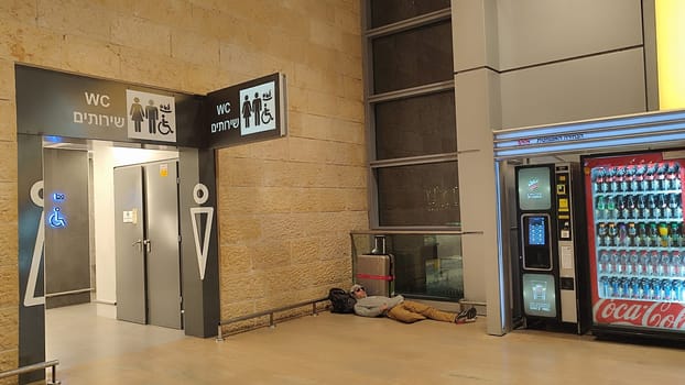 15 October 2024 Tel-Aviv Israel Ben Gurion airport Terminal 3, travel lounge, Male tourist sleeping on the floor near a suitcase, quality photo