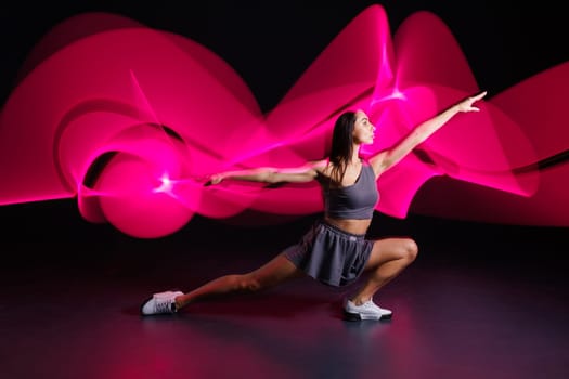 young girl athlete doing sports in neon light on dark background, concept modern sports training