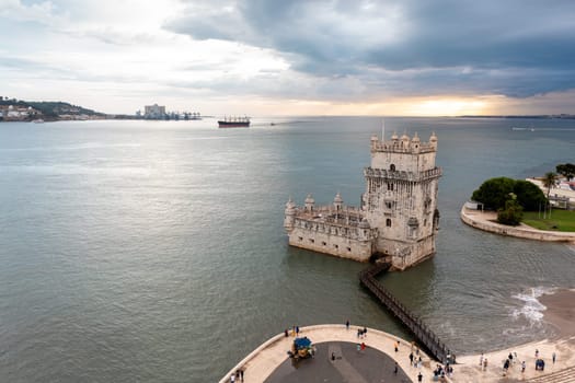 Aerial view Belem Tower. Fortress monument in Lisbon on Tagus River. 16th-century fortification Torre de Belem in city under cloudy sky.