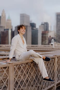 A stylish young man is enjoying a peaceful moment on a rooftop as he gazes at a breathtaking and vibrant city skyline