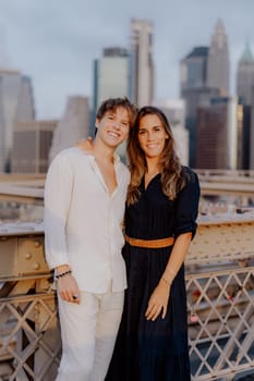 A lovely couple shares a sweet, tender kiss on the iconic Brooklyn Bridge, with the stunning NYC skyline behind them