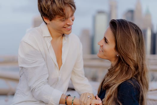 A lovely couple shares a sweet, tender kiss on the iconic Brooklyn Bridge, with the stunning NYC skyline behind them