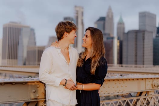 A lovely couple shares a sweet, tender kiss on the iconic Brooklyn Bridge, with the stunning NYC skyline behind them