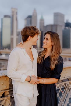 A lovely couple shares a sweet, tender kiss on the iconic Brooklyn Bridge, with the stunning NYC skyline behind them