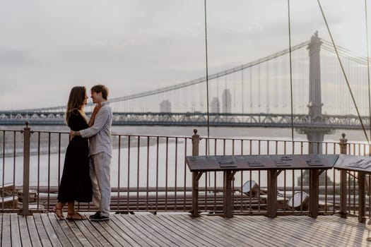 A beautifully romantic moment was captured between an affectionate couple, framed by a stunning bridge backdrop. Manhattan and Brooklyn bridge in New York.