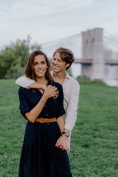 A lovely couple shares a delightful and romantic moment outdoors, right next to the iconic Brooklyn Bridge