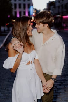 A young couple is happily enjoying a romantic and intimate moment amidst the vibrant cityscape at dusk