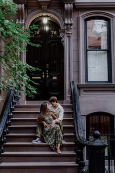A couple shares a peaceful and quiet moment together on the steps of a charming urban brownstone building