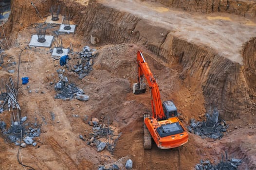 excavator digs the ground under the foundation pit at a construction site