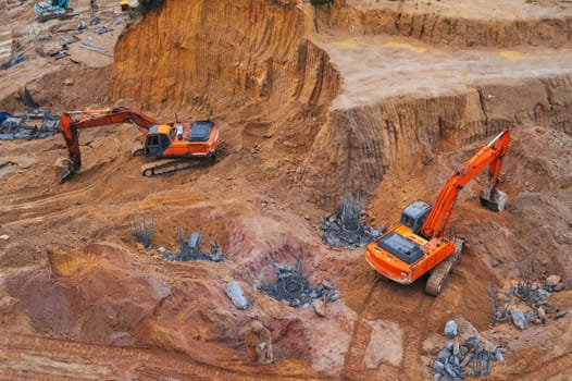 Excavators dig the ground in the foundation pit of a building on a construction site. View from above