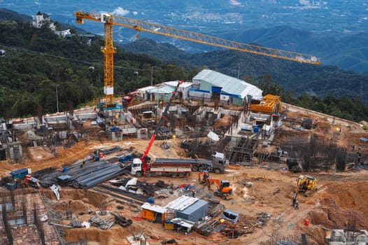 A construction site with a crane and an excavator. Development of a foundation pit for a building under construction. View from above