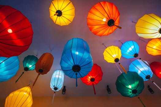 Traditional multicolored silk hanging Chinese lanterns from the ceiling of an Asian cafe for interior decoration