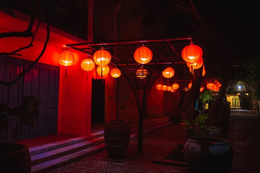 Glowing red traditional paper Chinese lanterns decorate the facade of a building in Asia at night