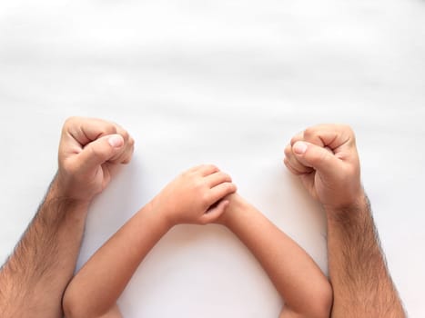 Parent and child fists together on white background symbolizing unity and support.