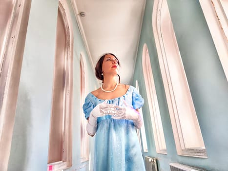 Dressed in elegant attire, a girl embodies a romantic princess while exploring the captivating interior of an ancient castle.