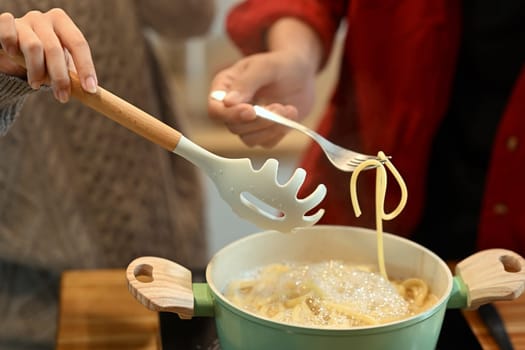 Young married couple preparing delicious pasta on Christmas Day.