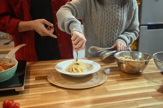 Cropped shot young couple preparing a warm pasta dish for festive meal in kitchen.