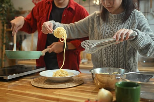 Young married beautiful couple in sweaters preparing dinner on Christmas Day in kitchen.