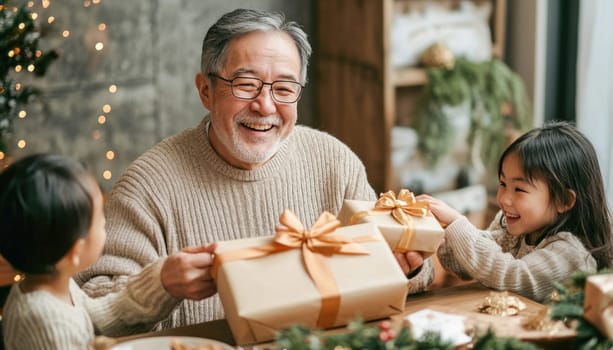 Happy grandfather giving christmas presents to his granddaughters during christmas celebration at home