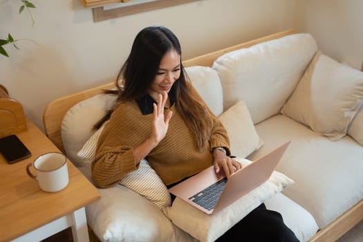 Cheerful woman having a video call on her laptop at home.