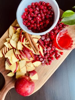 white bowl full of cranberries and apple slices on cutting board, ingredients for making fruit drink. High quality photo.