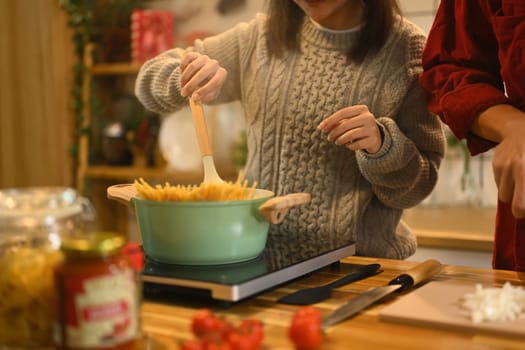 Young married beautiful couple in sweaters preparing dinner on Christmas Day in kitchen.