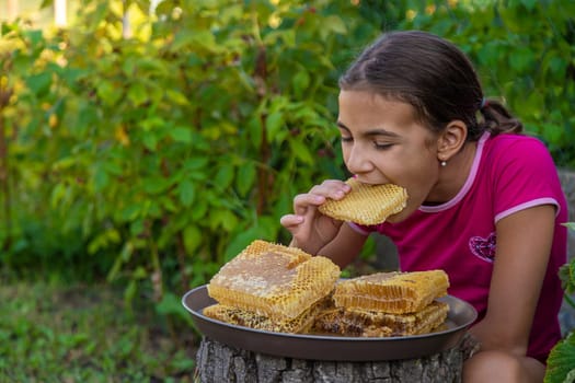 A child eats honey from a comb. Selective focus. Kid.