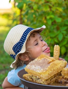 A child eats honey from a comb. Selective focus. Kid.