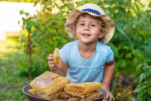A child eats honey from a comb. Selective focus. Kid.